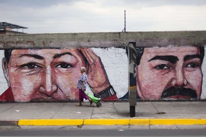Una mujer pasa frente a un muro con una pintada de Chávez y Maduro.