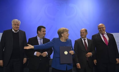 A chanceler alemã, Angela Merkel, mostra o documento assinado por vários ministros, empresários e sindicalistas para acelerar a entrada de trabalhadores qualificados na Alemanha, depois da reunião sobre o tema em Berlim.