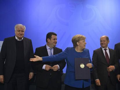 La canciller alemana, Angela Merkel, muestra el documento que permitirá acelerar la entrada de trabajadores cualificados en Alemania, este lunes en Berlín.