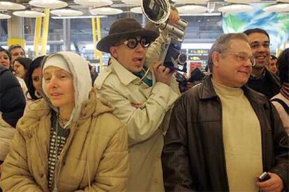 Un actor <i>infiltrado</i> en un grupo de viajeros saca fotos en el primer día de funcionamiento de la terminal 4 del aeropuerto de Barajas.