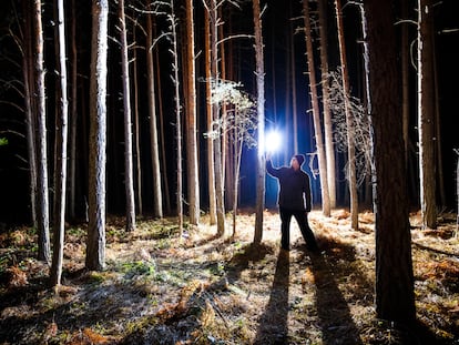Un hombre ilumina el interior de un bosque con una luz led.