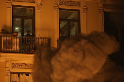 Vecinos de un edificio del centro de Barcelona observan el humo provocado por una de las barricadas incendiadas, en la tercera noche de protestas por el encarcelamiento de Pablo Hasél.