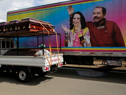 Un camión con ataúdes pasa junto a una pancarta del presidente de Nicaragua, Daniel Ortega y su esposa, Rosario Murillo, colocada en una clínica móvil, en de noviembre de 2021 en Masaya.
