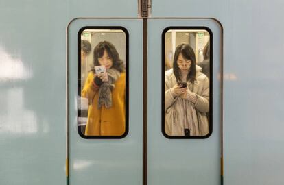 Dos mujeres consultan sus teléfonos móviles mientras viajan en el metro de la ciudad de Chongqing (China). 