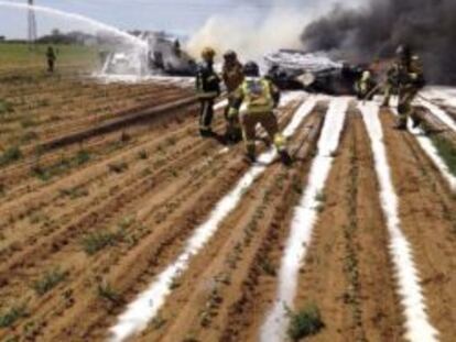 Bomberos extinguiendo el incendio provocado por el accidente del avión militar en los alrededores de Sevilla.