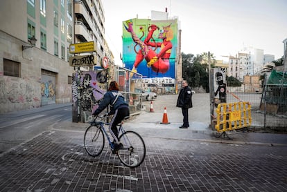 Fernando, el encargado del aparcamiento de los vendedores del mercado, con el mural de Margarida al fondo pintado en una pared que se quedó al descubierto por el derrumbe de las edificios anexos hace años, entre las calles de Murillo y Moro Zeit de Valencia. 