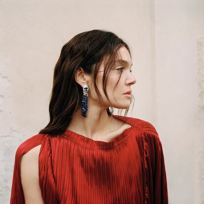Vestido plisado en satén de seda de HERMÈS y pendientes Serpenti de la colección de alta joyería Mediterranea de BVLGARI en platino con 2 zafiros ovales, 103 cuentas de zafiro, 4 diamantes en forma de pera, 4 diamantes ovales, 2 diamantes triangulares, 30 diamantes redondos talla brillante y pavé de diamantes.