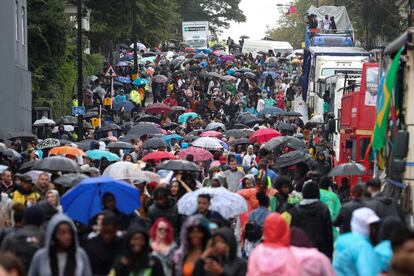 Asistentes se refugian de la lluvia bajo sus paraguas en el primer día del Carnaval de Notting Hill. 