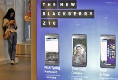 Fotograf&iacute;a fechada el 9 de mayo de 2013 que muestra a una ciudadana tailandesa junto a un cartel publicitario del nuevo modelo de m&oacute;vil BlackBerry 10, en Bangkok, Tailandia. 