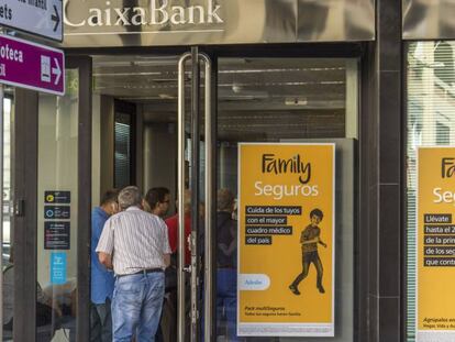 Varios clientes esperan para acceder a una oficina de CaixaBank.