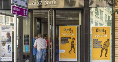 Varios clientes hacen cola en una oficina de CaixaBank.