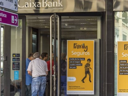Varios clientes hacen cola en una oficina de CaixaBank.