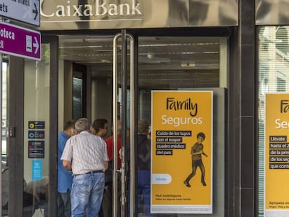 Varios clientes esperan para acceder a una oficina de CaixaBank.