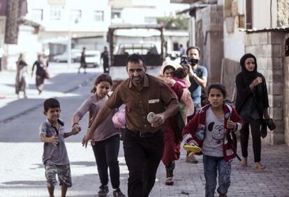 Una familia corre para ponerse a salvo de los disparos de mortero, en la ciudad fronteriza de Akcakale (Turquía).