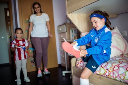 Candela Caballero se pone las zapatillas de deporte en su dormitorio junto a su madre y su hermana.