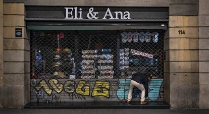 Una persona echa el cierre a un comercio en Barcelona.