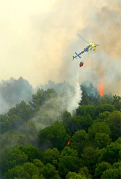 Un helicptero vierte agua sobre una de las reas afectadas por el fuego.