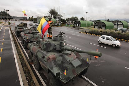 Un soldado sujeta una bandera colombiana en lo alto de un tanque, en las afueras de Bogotá, este martes