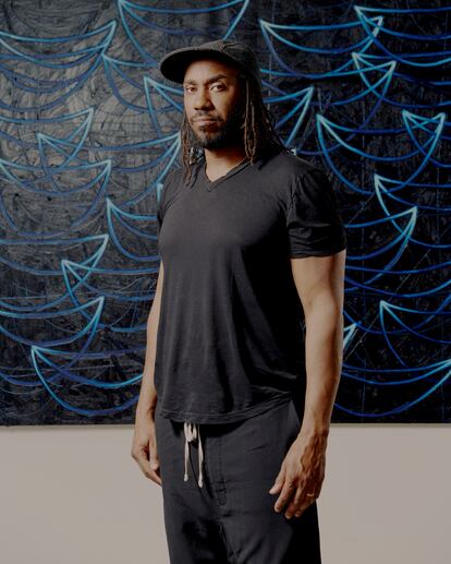 El artista Rashid Johnson en su estudio en Brooklyn, Nueva York, con una obra de la serie 'Seascapes' al fondo. 