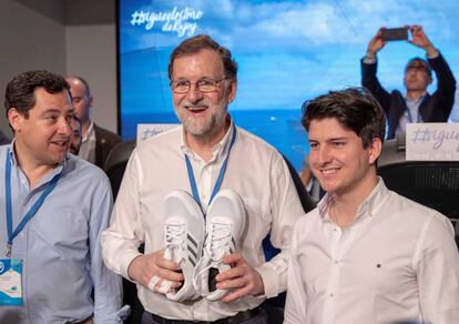 Mariano Rajoy, acompañado de líder andaluz, Juanma Moreno (i), recibió unas zapatillas de regalo del presidente de Nuevas Generaciones, Diego Gago (d), el 7 de abril de 2018.