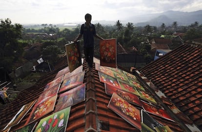 Un artista de Jelekong, en Java, camina por el tejado de su casa donde pone a secar los cuadros que después venderá para ganarse la vida.
