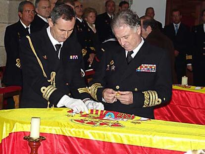 El almirante Zaragoza, a la derecha, prende una medalla sobre el féretro de uno de los marineros.