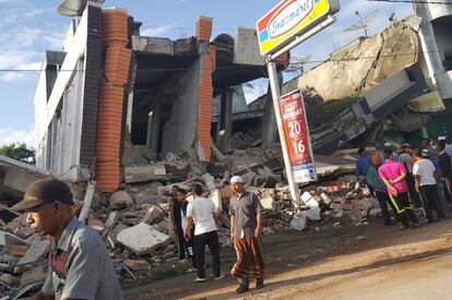 Varias personas caminan junto a los escombros de un edificio destruido tras el terremoto, en Pidie Jaya (Indonesia).