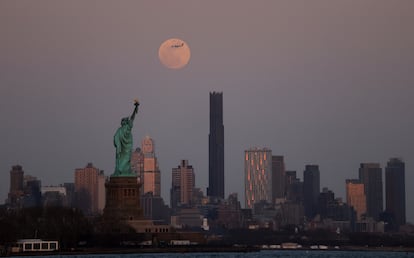 La Luna llena sobre el horizonte de Brooklyn y la Estatua de la Libertad en Nueva York (EE UU).