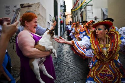 Una mujer con un perro observa a los participantes en Alfama de camino al desfile de San Antonio de Lisboa, en la Avenida de la Libertad.