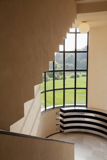La escalera principal se ilumina gracias a un gran ventanal con vistas al jardín. Las líneas en aluminio del cubre-rradiador subrayan su diseño curvo.
