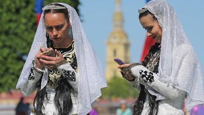 Dos mujeres comprueban sus m&oacute;viles en el Desfile de las Nacionalidades, en la Avenida Nevski de San Petesburgo en mayo de 2018. 