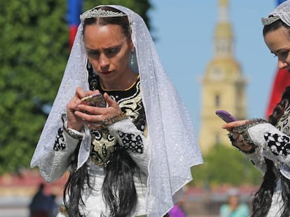 Dos mujeres comprueban sus m&oacute;viles en el Desfile de las Nacionalidades, en la Avenida Nevski de San Petesburgo en mayo de 2018. 