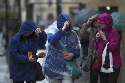 Varias mujeres se protegen de la lluvia y viento con impermeables de plástico, en Sevilla. 
 