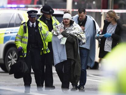 Dois feridos são ajudados por policiais na região de Westminster.