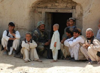 Un soldado afgano acompañado de civiles, entre ellos varios niños,  en una aldea al suroeste de Kandahar, en Afganistán.