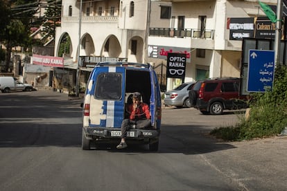 A young man smokes in the back of the van on a road in southern Lebanon.