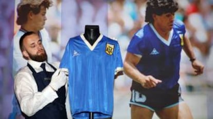 Un técnico de Sotheby's ajusta una camiseta de fútbol que usó el argentino Maradona contra Inglaterra en el Mundial de 1986.