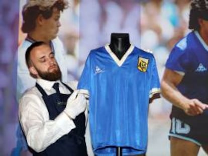 Un técnico de Sotheby's ajusta una camiseta de fútbol que usó el argentino Maradona contra Inglaterra en el Mundial de 1986.