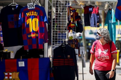 Una señora mira una camiseta de Leo Messi en una tienda cercana a las instalaciones del Camp Nou.