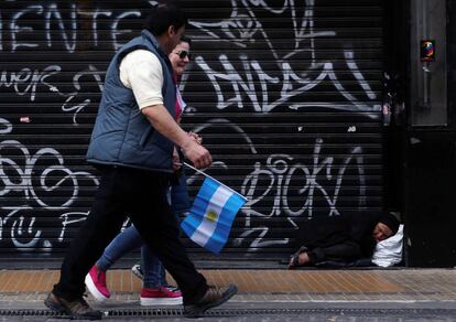 Mulher dorme na cal&ccedil;ada enquanto pessoas caminham durante a celebra&ccedil;&atilde;o do bicenten&aacute;rio da independ&ecirc;ncia argentina, em Buenos Aires. 