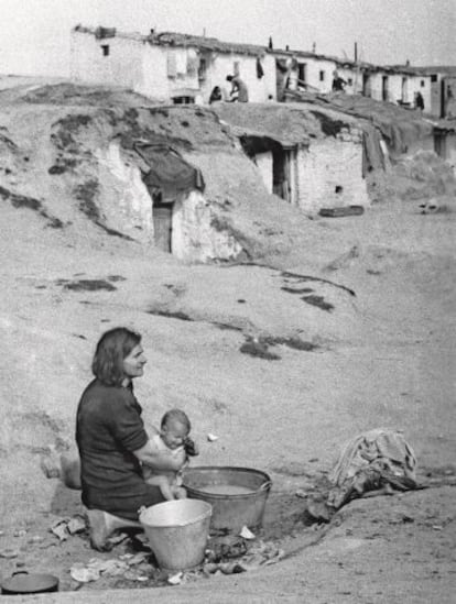Una mujer ba&ntilde;a a su hijo en un balde, en un barrio de chabolas a las afueras de Madrid en abril de 1940.