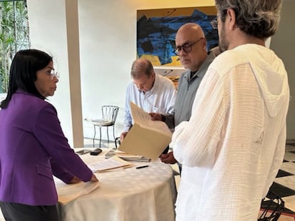 Edmundo González (centro izquierda) firma un documento en la presencia de Jorge Rodríguez, presidente de la Asamblea de Venezuela,. y la vicepresidenta ejecutiva del país, Delcy Rodríguez.