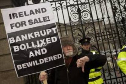 Un hombre porta una pancarta durante una manifestación en contra de los Presupuestos Generales ante el Parlamento irlandés en Dublín. EFE/Archivo