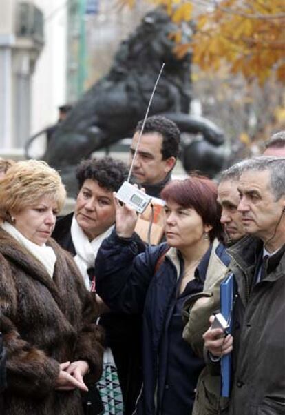 Familiares y amigos de víctimas del 11-M siguen a través de un transistor la intervención de Pilar Manjón en la comisión de investigación parlamentaria.