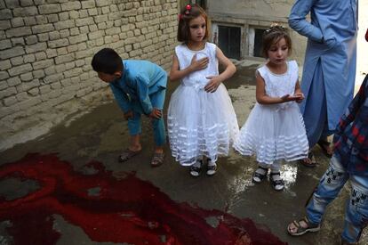 Dos niñas junto a un charco de sangre miran como degollan a un cordero (fuera de plano) en Kabul, Afganistán, el 21 de agosto de 2018.