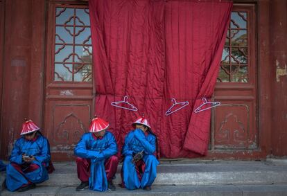 Actores vestidos con trajes tradicionales descansan durante el ensayo de la recreación del ritual de sacrificio imperial de la dinastía Qing, en Pekín (China).