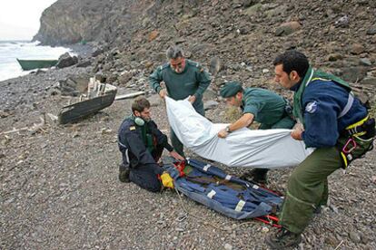 Dos agentes y dos tripulantes de un helicóptero colocan en una camilla el cuerpo del inmigrante fallecido.