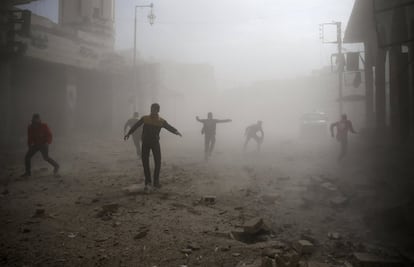 Un grupo de hombres corre tras un ataque aéreo a la población en Douma, al este de Damasco (Siria). 