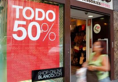 Una mujer pasa por delante de una tienda de moda en Madrid que desde hoy anuncia las rebajas de verano.