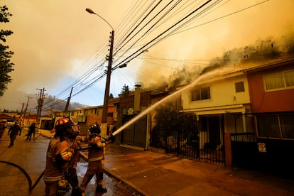 Una cuadrilla de bomberos rocía agua sobre los tejados de las viviendas de un barrio de Viña del Mar, el 3 de febrero de 2024. 